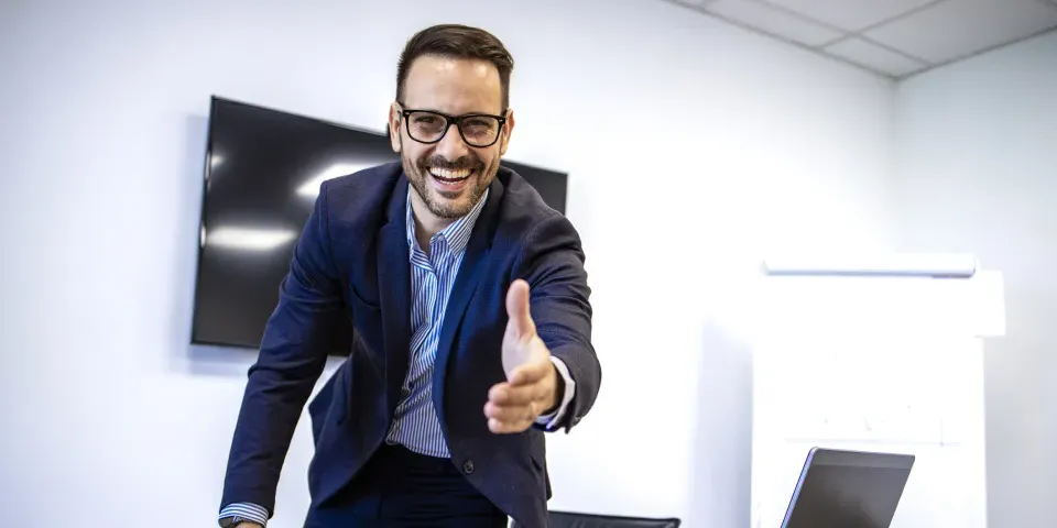 Portrait of businessman in elegant suit showing welcoming hand to the new employees.